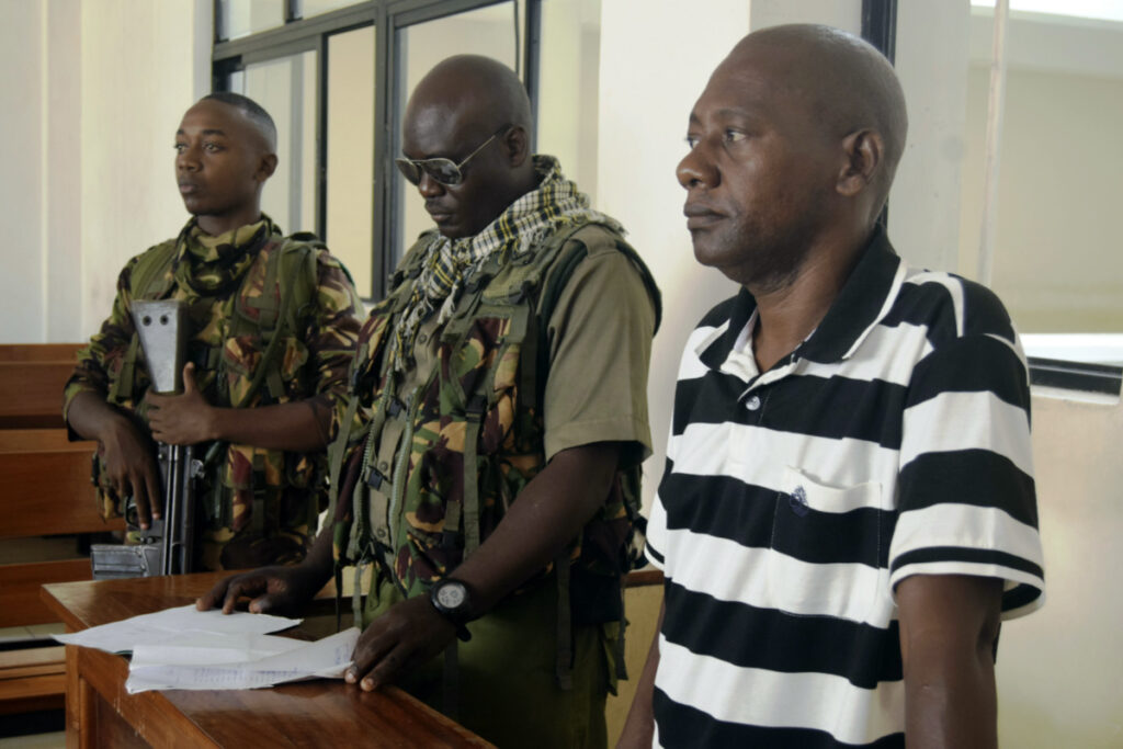 Cult preacher Pastor Paul Nthenge Mackenzie, right, stands at the Malindi Law Courts under tight security, on Friday 1st December, 2023