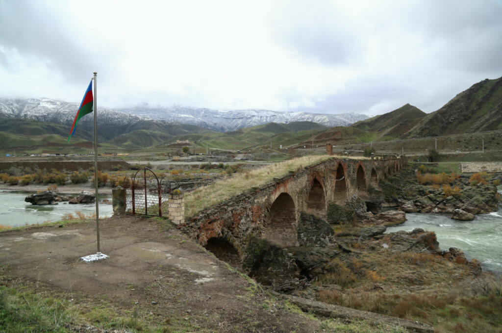 An Azerbaijani national flag is seen next to the ancient Khodaafarin Bridge near the border with Iran in the area, which came under the control of Azerbaijan's troops following a military conflict over Nagorno-Karabakh against ethnic Armenian forces and a further signing of a ceasefire deal, in Jabrayil District, on 7th December, 2020.
