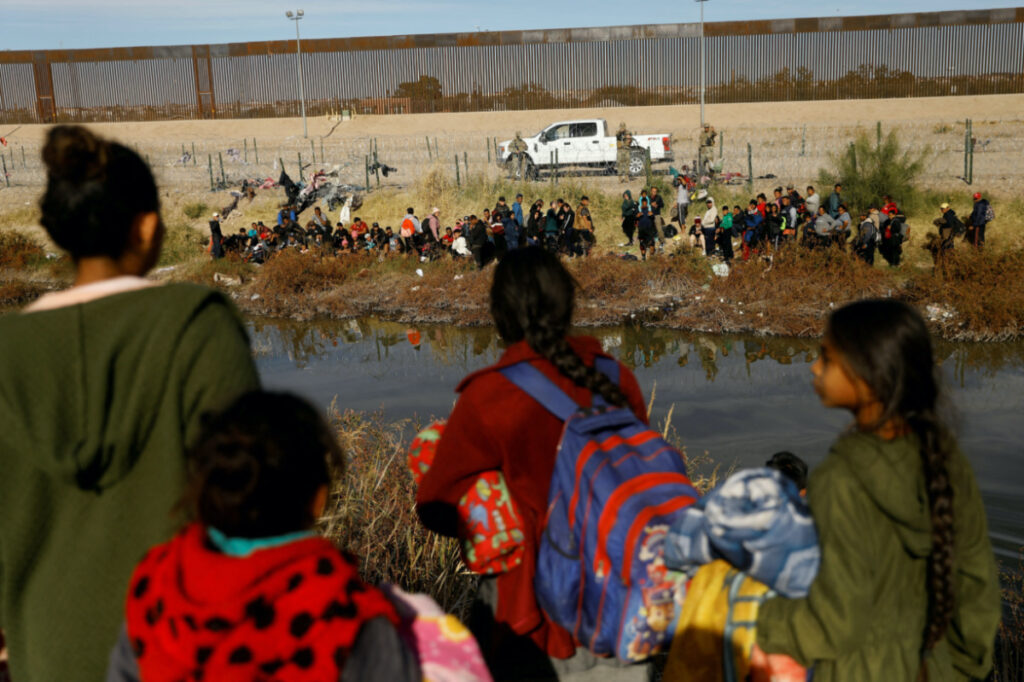 Migrants seeking asylum in the United States gather on the banks of the Rio Bravo river, as the Texas National Guard blocks the crossing at the border between the United States and Mexico, as seen from Ciudad Juarez, Mexico, on 5th December, 2023
