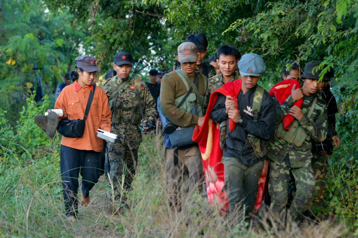 People's Liberation Army PLA members, carry an injured person as they fight the Myanmar junta army near Sagaing Region in Myanmar on 23rd November, 2023