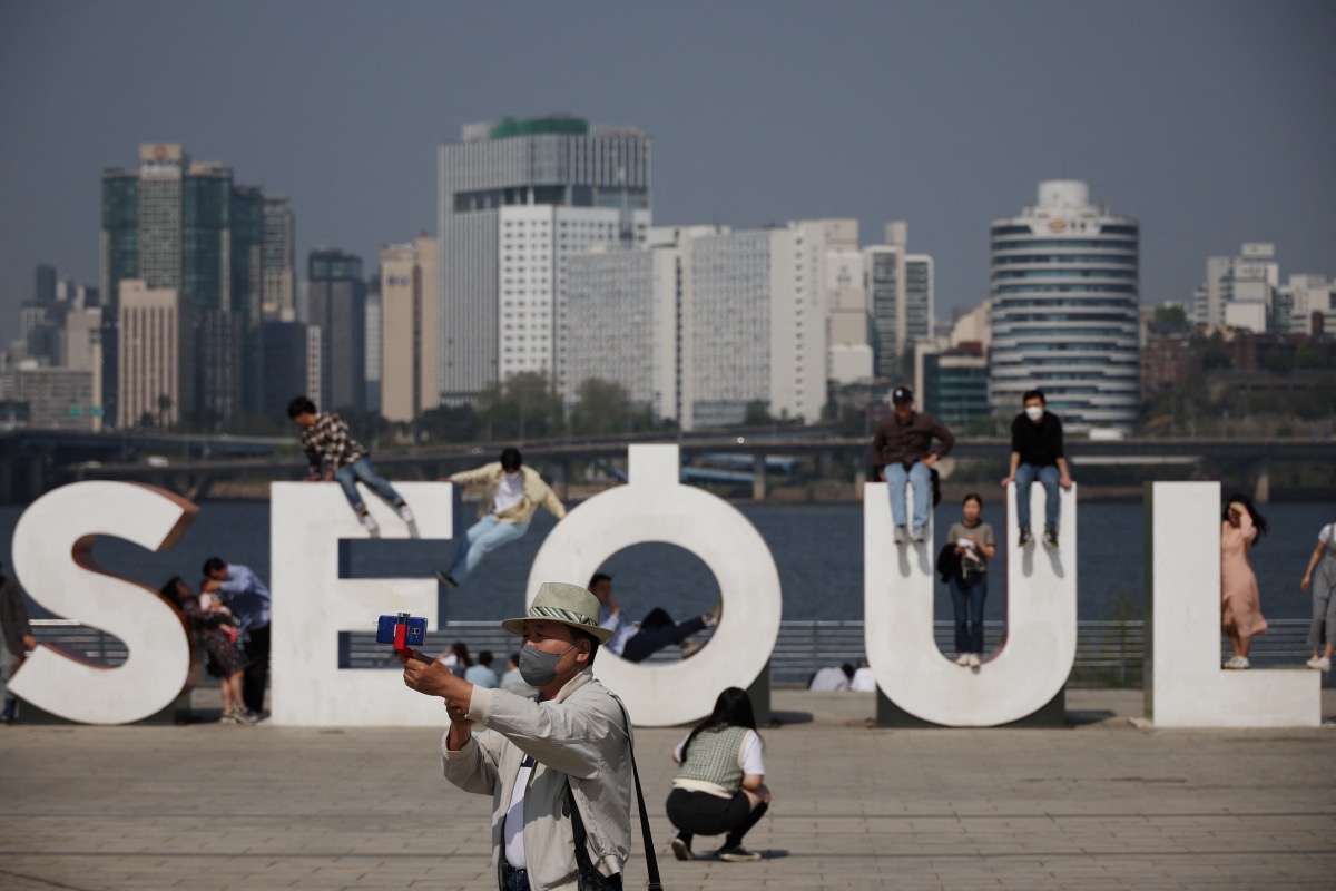 People pose for photographs on a sunny spring day amid the coronavirus disease pandemic at a Han river park in Seoul, South Korea, on 19th April, 2022.