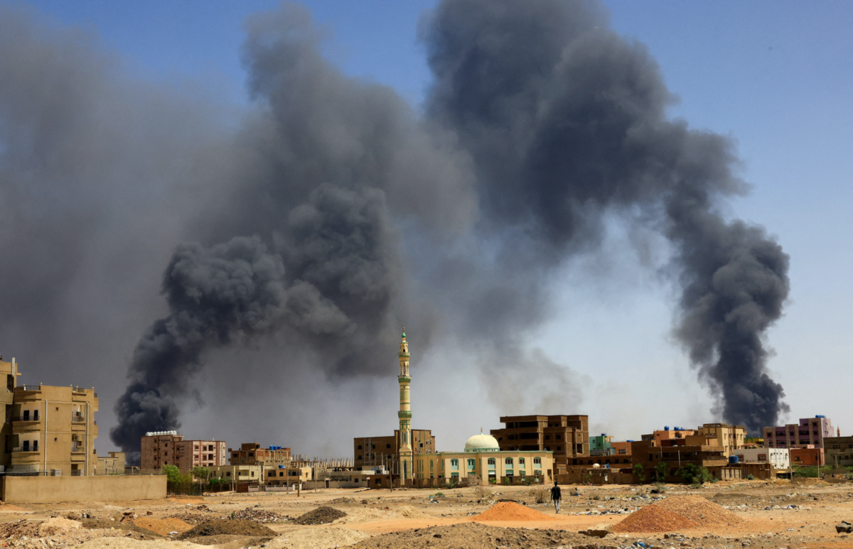 A man walks while smoke rises above buildings after aerial bombardment, during clashes between the paramilitary Rapid Support Forces and the army in Khartoum North, Sudan, on 1st May, 2023. 