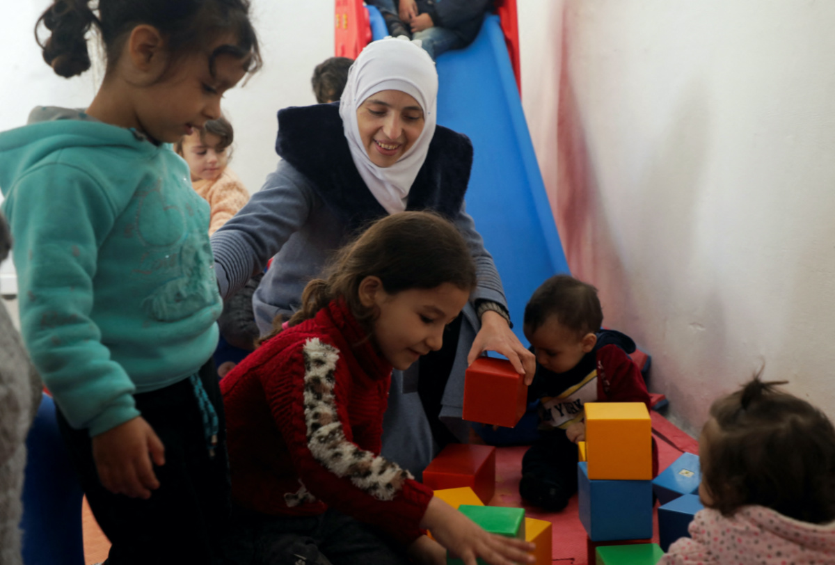 Safaa Kamel, 35, a teacher who says she suffered health effects following a gas attack on her home region of Eastern Ghouta in Syria in 2013 and, now displaced to the north-western Syrian region of Afrin, plays with children at a school in the northern Syrian town of Afrin, Syria on 28th November, 2023