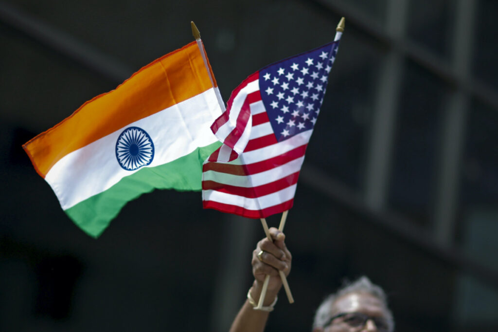 A man holds the flags of India and the US while people take part in the 35th India Day Parade in New York on 16th August, 2015