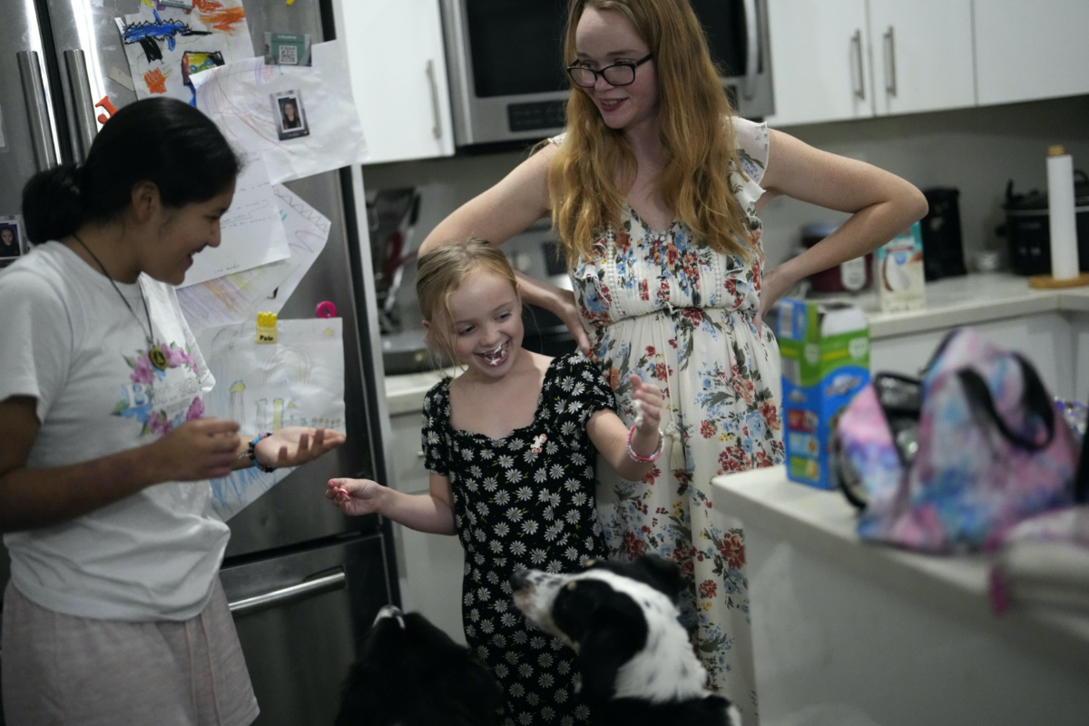 Sol, left, a 14-year-old from Argentina, and eight-year-old Maddie Hazelton joke around with some whipped cream as Sol's foster mother, Caroline Hazelton, and the family's two dogs look on, in Homestead, Florida, on Monday, 18th December, 2023