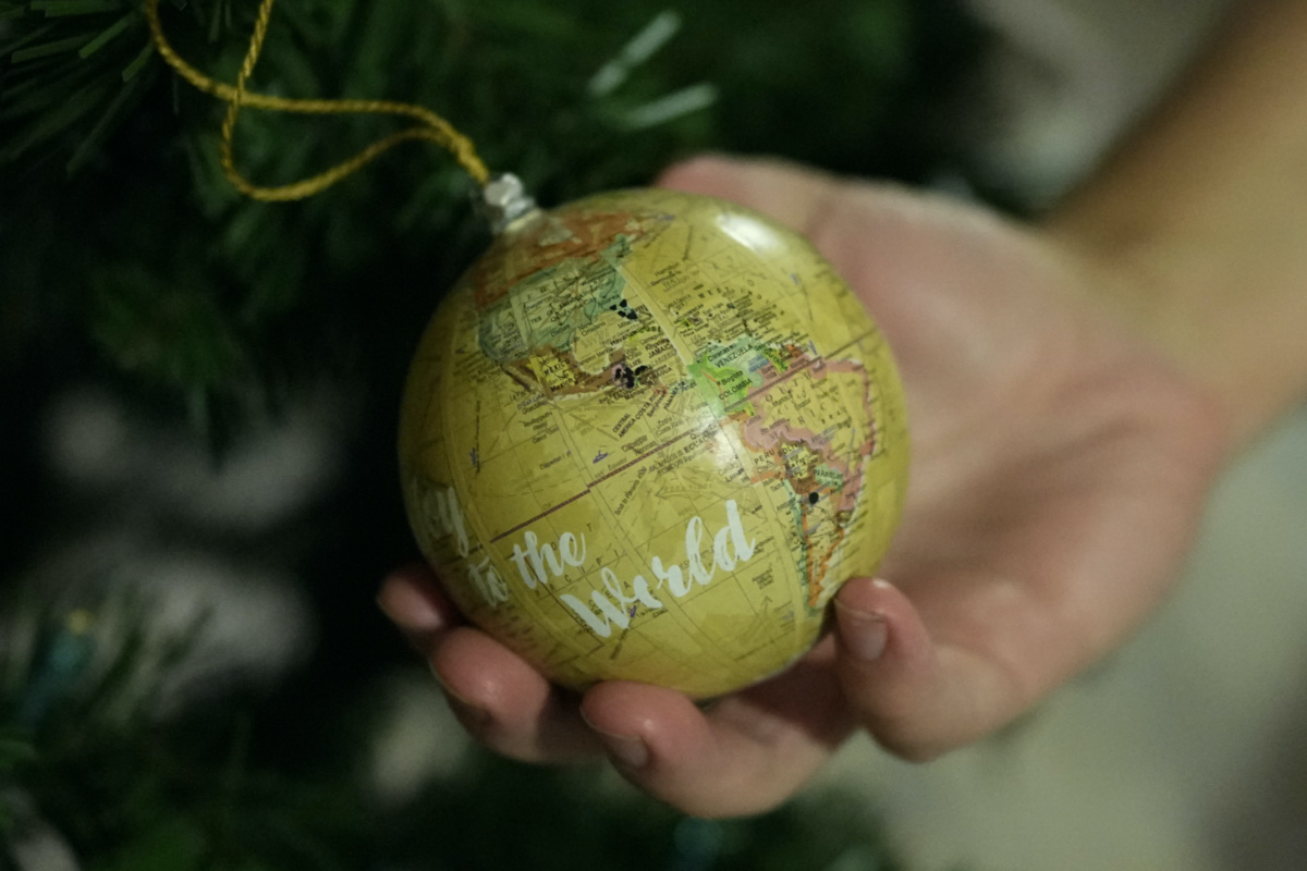 Andy Hazelton holds a globe ornament on which he and his wife have marked the home countries of migrant kids they have fostered, on the family's Christmas tree in Homestead, Florida, on Monday, 18th December, 2023.