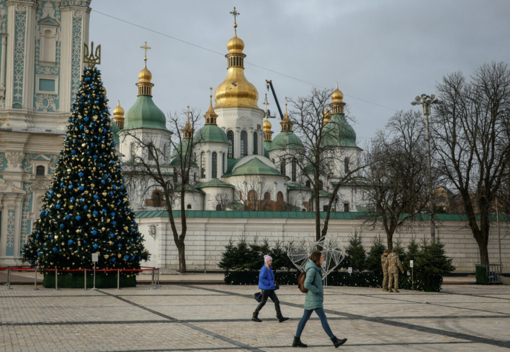 People walk near a Christmas tree in front of the Saint Sophia Cathedral as Ukrainians around the country are gearing up to celebrate their first Christmas according to a Western calendar, amid Russia's attack on Ukraine, in Kyiv, Ukraine, on 20th December, 2023.