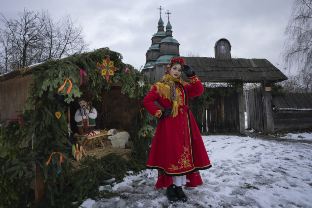 A woman dressed in national costume stands near the nativity scene to celebrate Christmas in the village of Pirogovo, outside the capital Kyiv, Ukraine, on Monday, 25th December, 2023