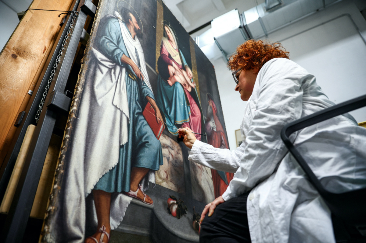 Restorer Alessandra Zarelli works on a painting at the "painting and wood materials restoration laboratory" inside the Vatican Museums, at the Vatican, on 11th December, 2023