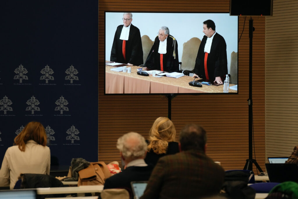 Reporters watch a screen showing Vatican tribunal president Giuseppe Pignatone reading the verdict of a trial against Cardinal Angelo Becciu and nine other defendants, in the Vatican press room, on Saturday, 16th December, 2023.
