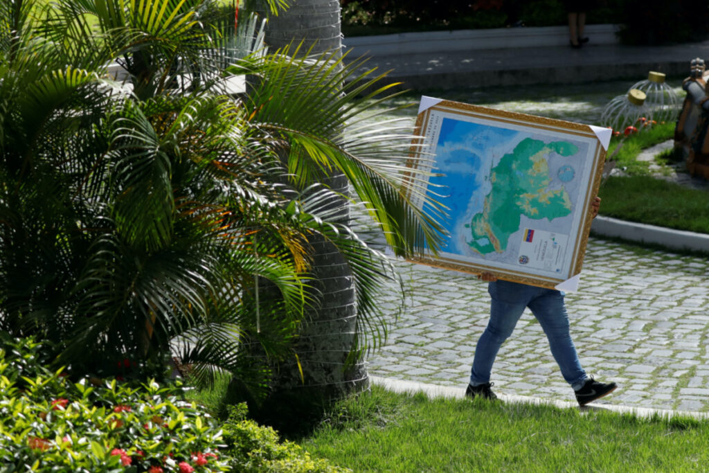 A man carries a framed map of Venezuela, showing the disputed Esequibo region as part of Venezuela, as tensions between Venezuela and Guyana have ratcheted up in recent weeks over a long-running territorial dispute, in Caracas, Venezuela on 6th December, 2023.