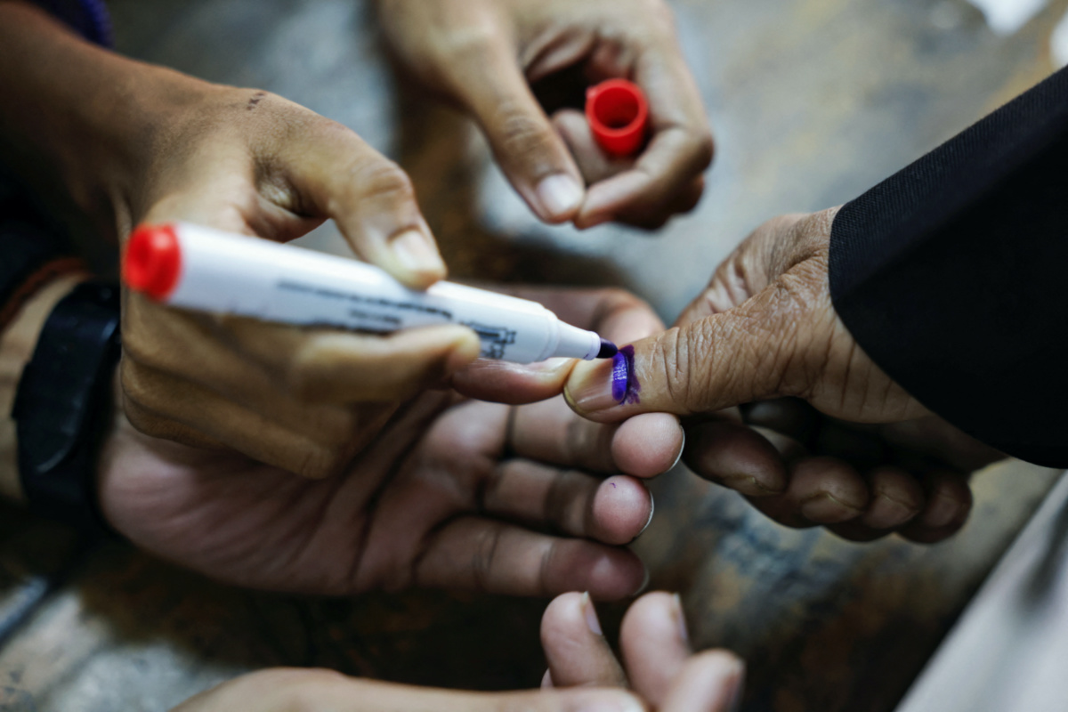 Officials mark the thumb of a voter with ink during the casting of vote in the 12th general election in Dhaka, Bangladesh, on 7th January, 2024.