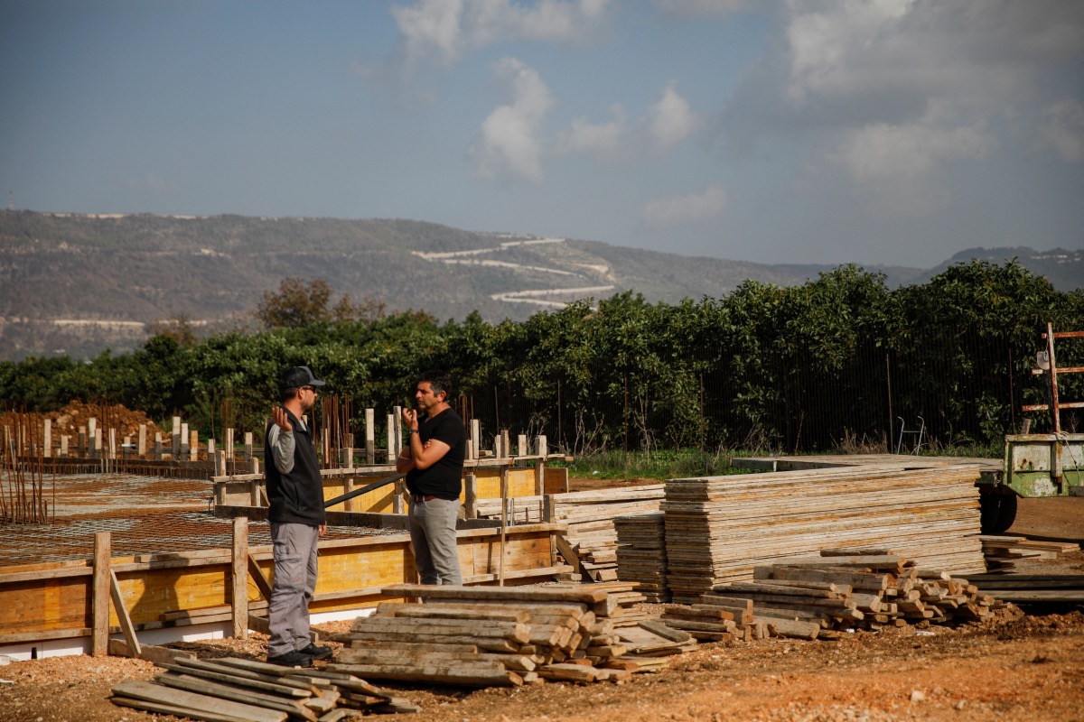 Men chat at a building site as Lebanon is seen in the background, in Liman, close the the Lebanese border in northern Israel, on 9th January, 2024