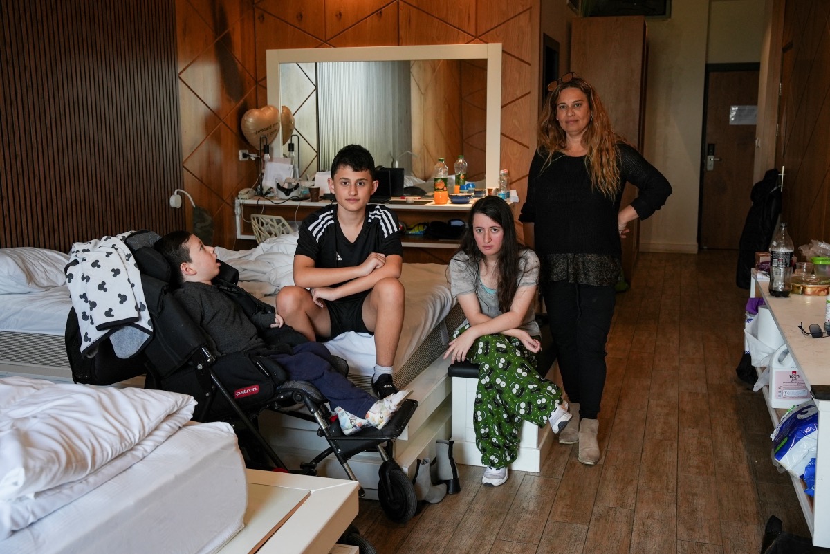 Dekel, Almog, Hadar and their mother, Riki Shusterman, pose for a picture in their temporary accommodation, after being evacuated from their home near the Lebanese border due to the ongoing cross-border hostilities between Hezbollah and Israeli forces, in the village of Regba, Israel, on 8th January, 2024