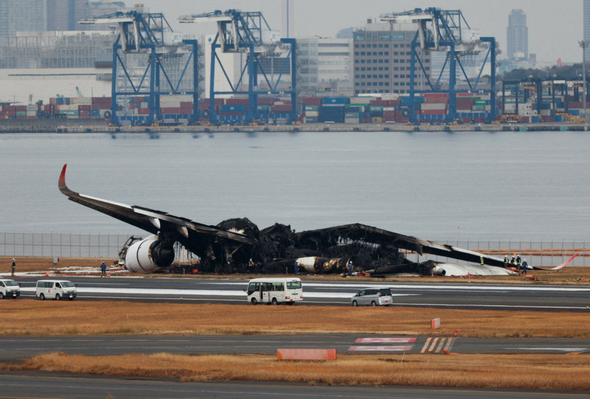 Officials investigate a burnt Japan Airlines Airbus A350 plane after a collision with a Japan Coast Guard aircraft at Haneda International Airport in Tokyo, Japan on 3rd January, 2024