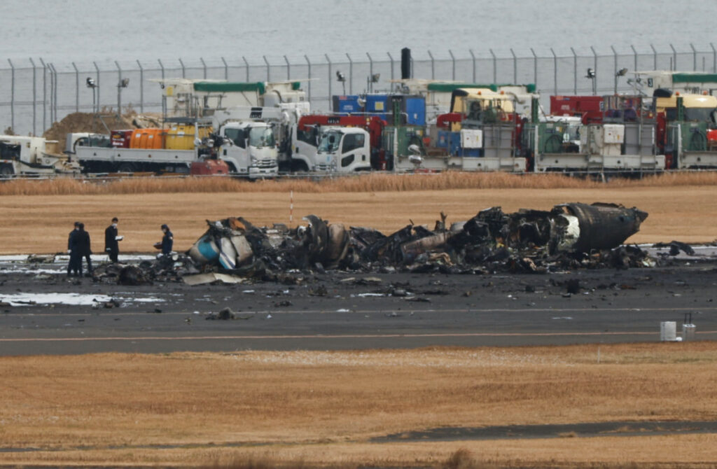 Officials investigate a burnt Japan Coast Guard aircraft after a collision with Japan Airlines' Airbus A350 plane at Haneda International Airport in Tokyo, Japan, on 3rd January, 2024