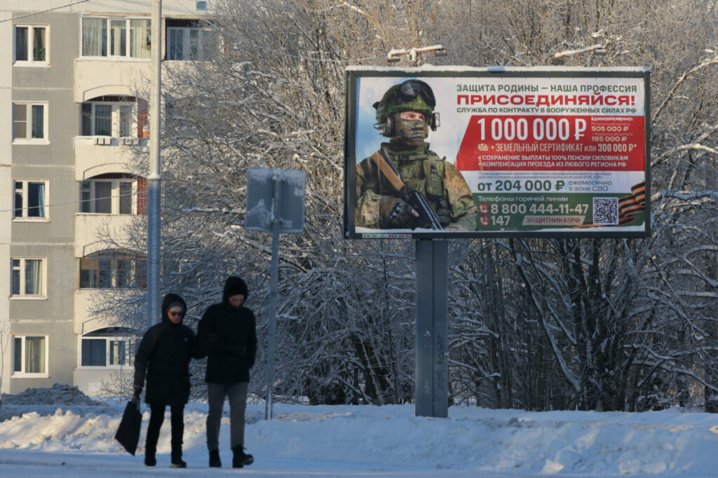 People walk along a street past a billboard promoting military service under the contract in Russian Armed Forces and containing information about payments in the town of Gatchina in Leningrad Region, Russia on 4th January, 2024.