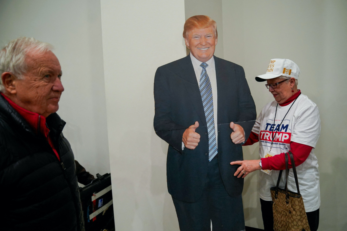 A supporter of former U.S President Donald Trump stands next to a cardboard cutout of him ahead of a campaign event for Trump hosted by US Representative Marjorie Taylor Greene, in Keokuk, Iowa, US, on 4th January, 2024